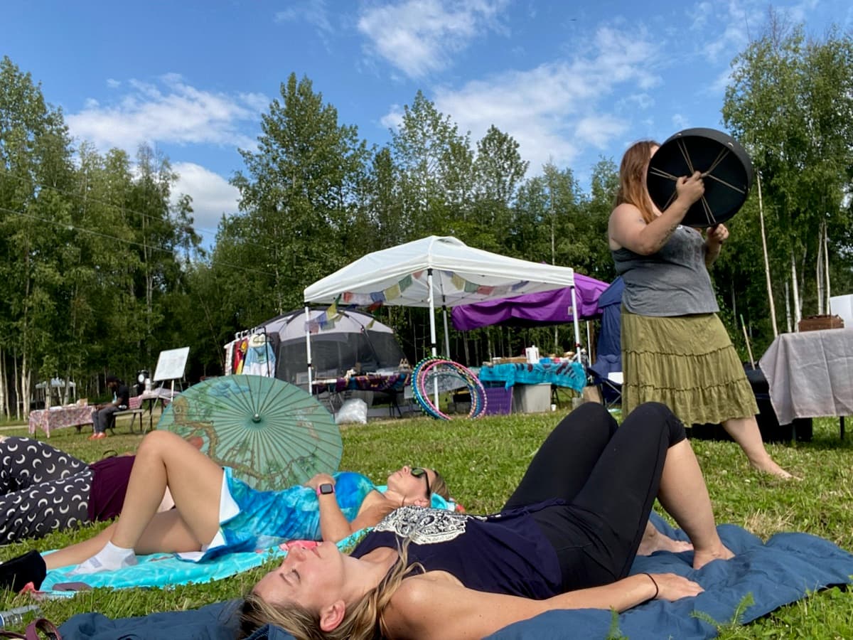 Women laying in grass drumming